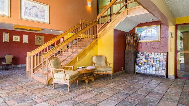 Eine Lobby mit Treppe, Sitzgelegenheiten und einem Schwarzes Brett.