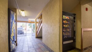 Ein Flur mit einem Getränkeautomaten, einer Treppe und einer Tür zum Ausgang.