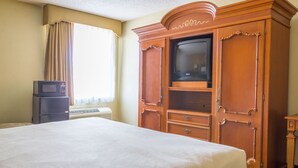 Ein Hotelzimmer mit einem großen Bett, einem Holzschrank, einem Fernseher und einer Mikrowelle.