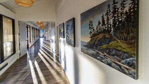 A hallway with wooden flooring, large windows, and artwork on the walls.