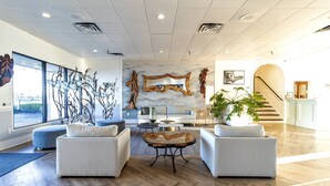A spacious lobby with modern furniture, a large mirror, and a staircase leading to another area.