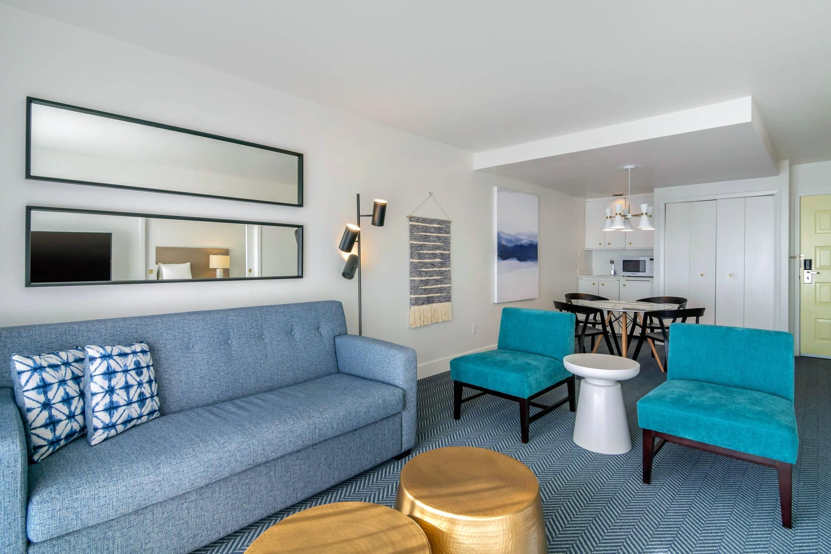 Una sala de estar moderna con un sofá, dos sillones, una mesa de centro y un comedor con una mesa y sillas.