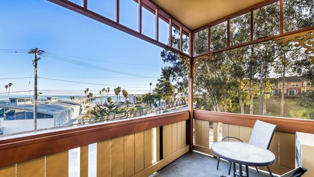 A balcony with a table and chairs, overlooking a street with palm trees and buildings. - Howard Johnson by Wyndham Santa Cruz (Santa Cruz)
