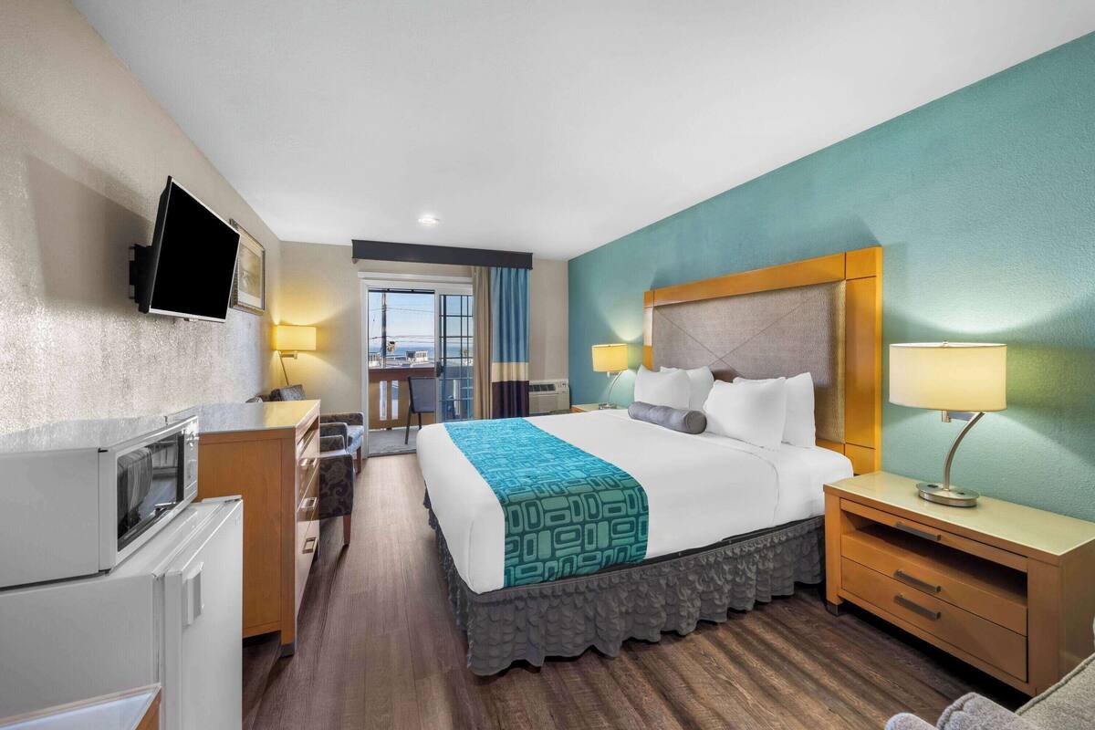 Een hotelkamer met een bed, nachtkastjes, een televisie, een bureau en uitzicht op de omgeving.