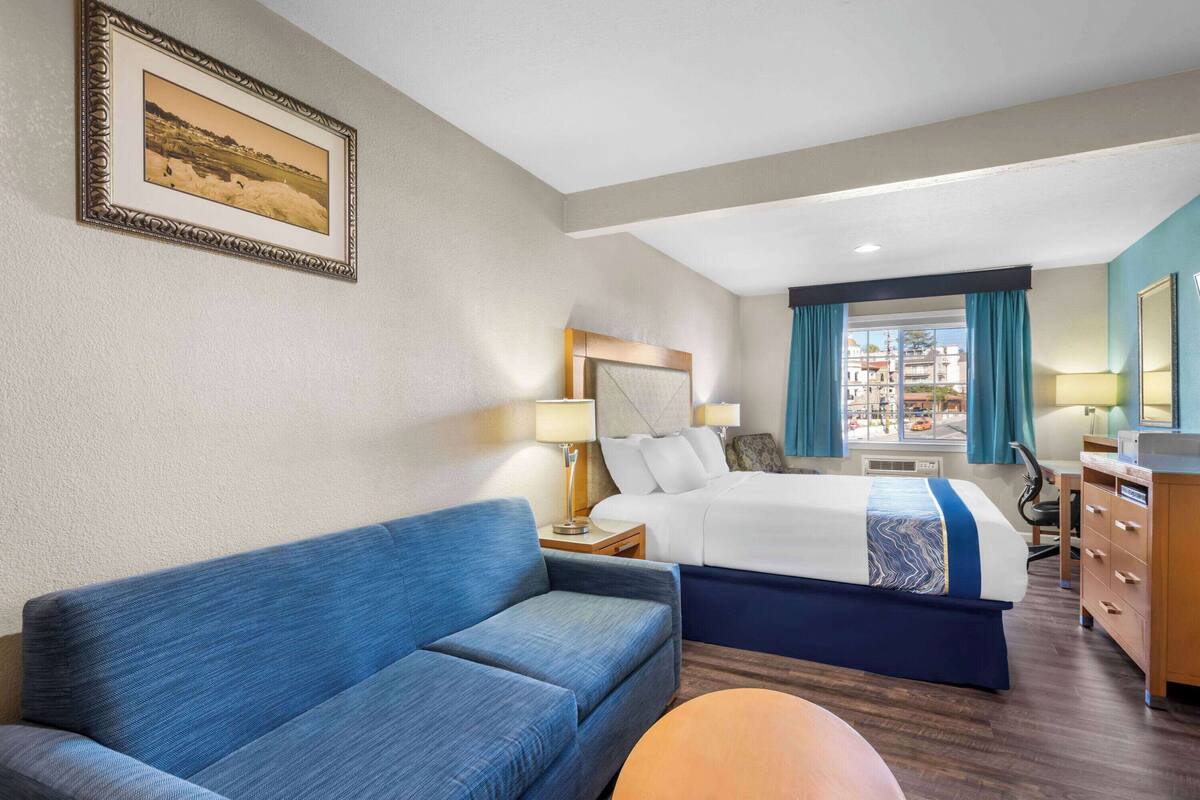 Een hotelkamer met een groot bed, een bank, een bureau en uitzicht op de stad.