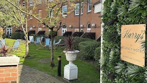 A courtyard with a brick building, outdoor seating, and a sign for Harry's at Regency Hotel.