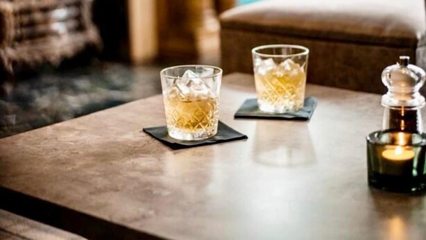 A table with two glasses of a clear liquid, possibly a beverage, with ice cubes. There is a candle in a glass holder on the table. - The Regency Hotel Solihull (Solihull)
