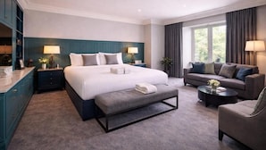 A modern hotel room with a large bed, a sofa, a bench, and a coffee table.