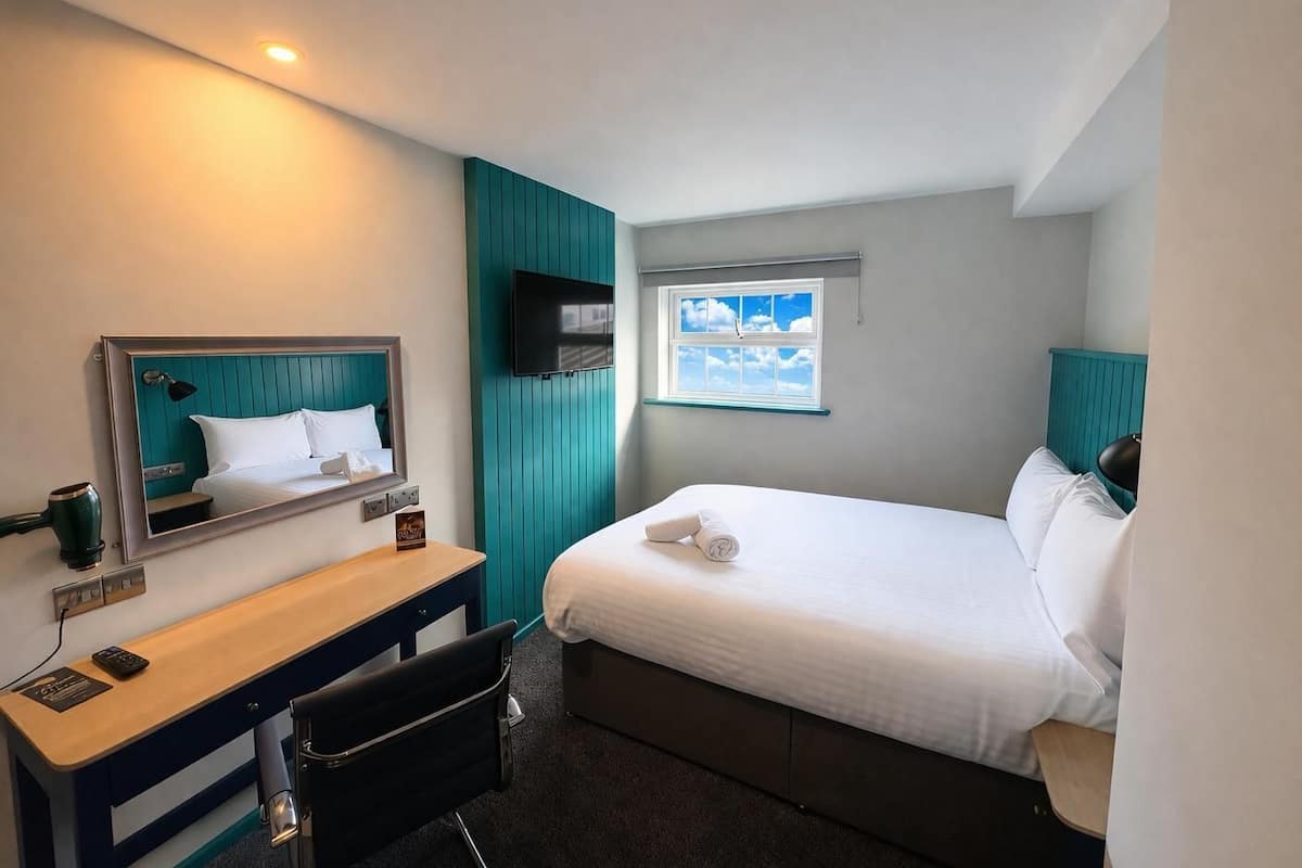 Ein Hotelzimmer mit Bett, Schreibtisch, Stuhl, Fernseher und einem Fenster mit Blick.
