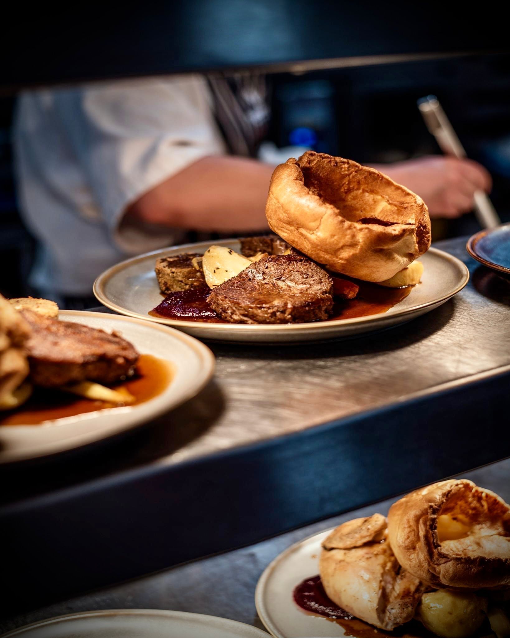 Gros plan d’une assiette contenant des Yorkshire puddings et de la viande, probablement du bœuf.
