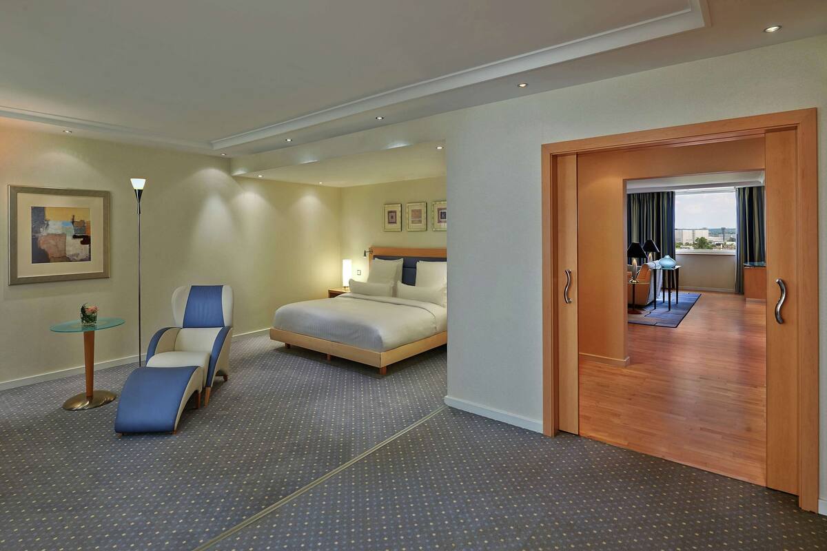 Een hotelkamer met een bed, een stoel, een tafeltje en uitzicht op de stad.