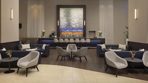 A modern lobby with a bar area, seating arrangements, and a decorative wall. - Hilton Düsseldorf (Düsseldorf)