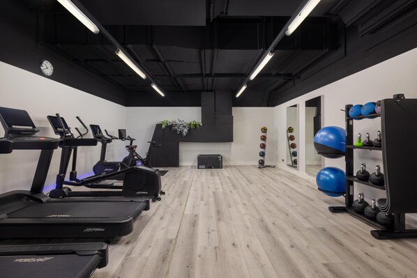 A gym with treadmills, stationary bikes, and a weight rack. - Hilton Düsseldorf (Düsseldorf)