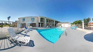 A pool area with lounge chairs and a building in the background.