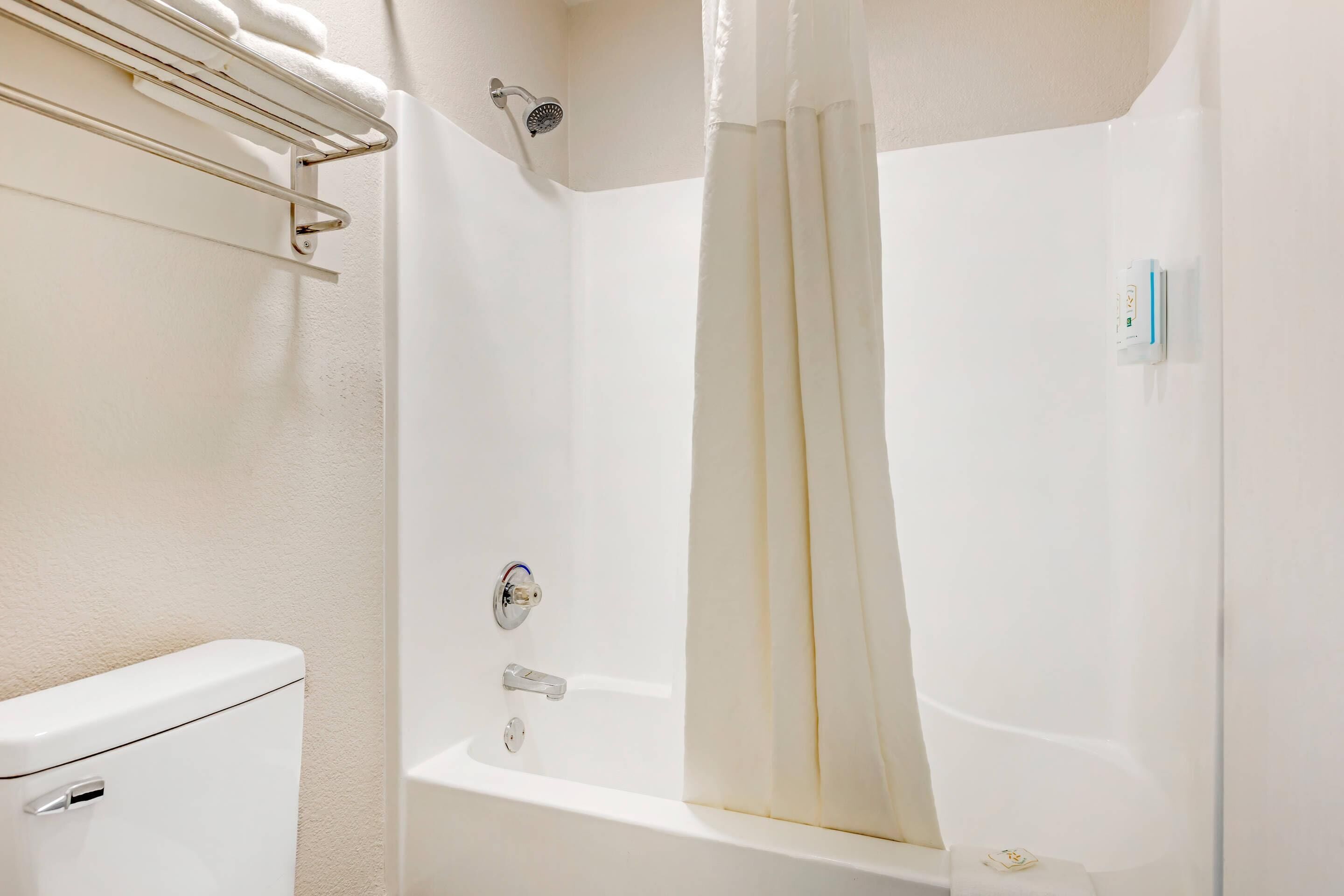 A bathroom with a bathtub, toilet, and towel rack.