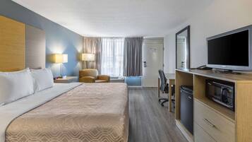 Camera d'albergo con un letto grande, una scrivania, una sedia, un televisore e un forno a microonde.
