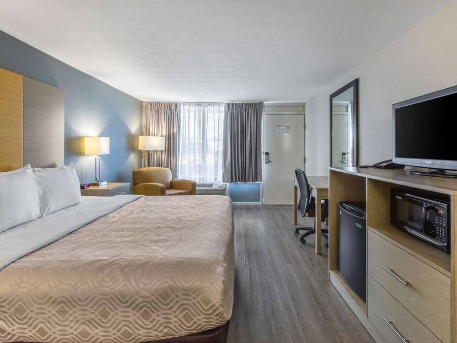 Camera d'albergo con un letto grande, una scrivania, una sedia, un televisore e un forno a microonde.
