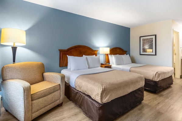 A hotel room with two beds, a sofa, and a lamp.
