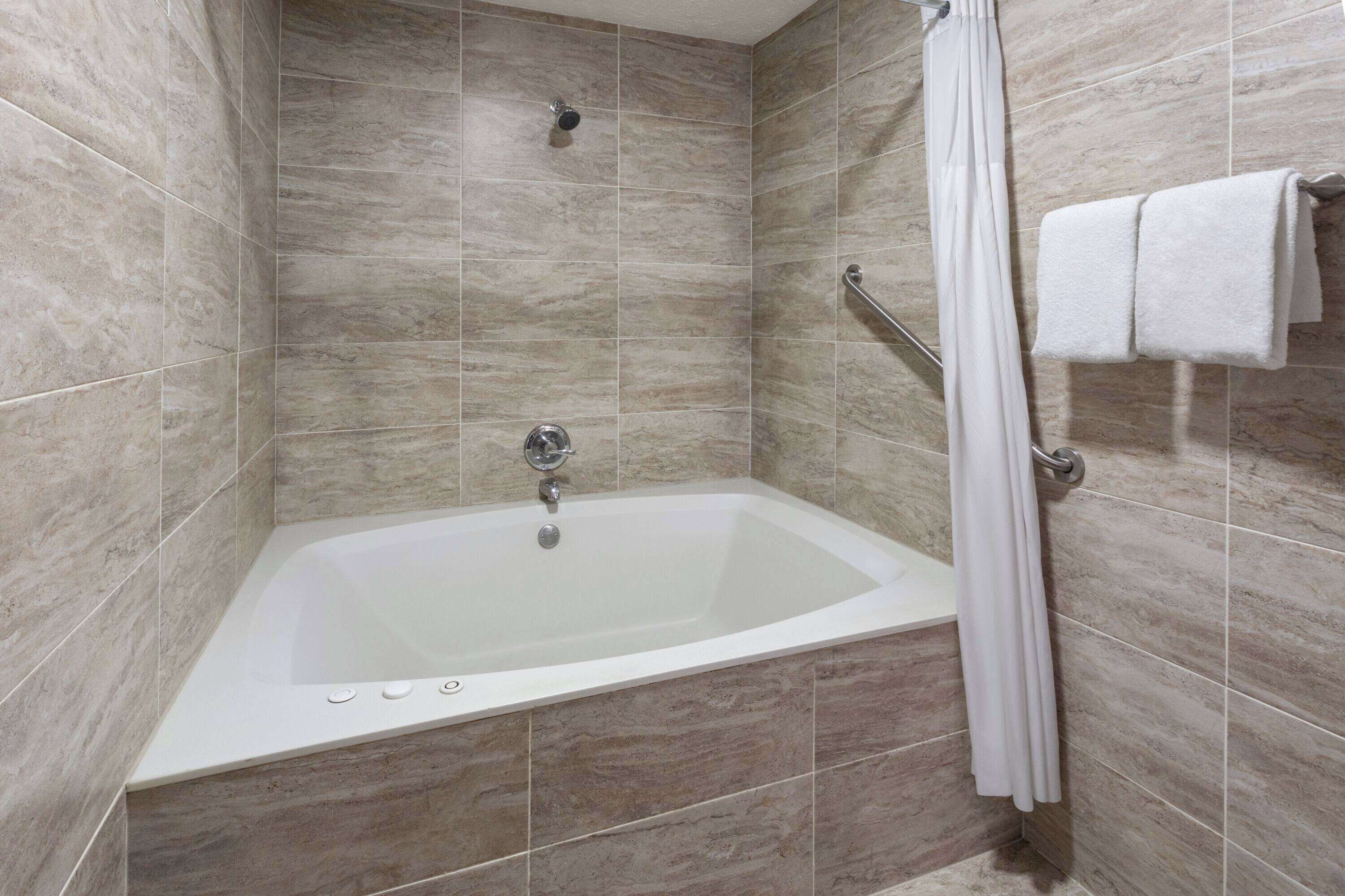Une salle de bain moderne avec une baignoire sur pieds, une pomme de douche et un porte-serviettes avec des serviettes.