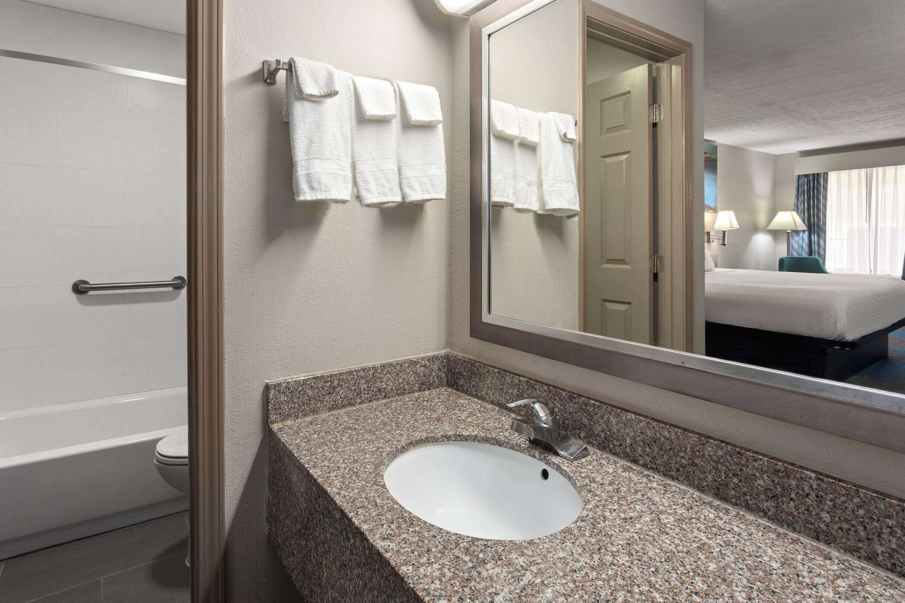 Bagno d'albergo con lavabo in granito, uno specchio e un porta asciugamani.