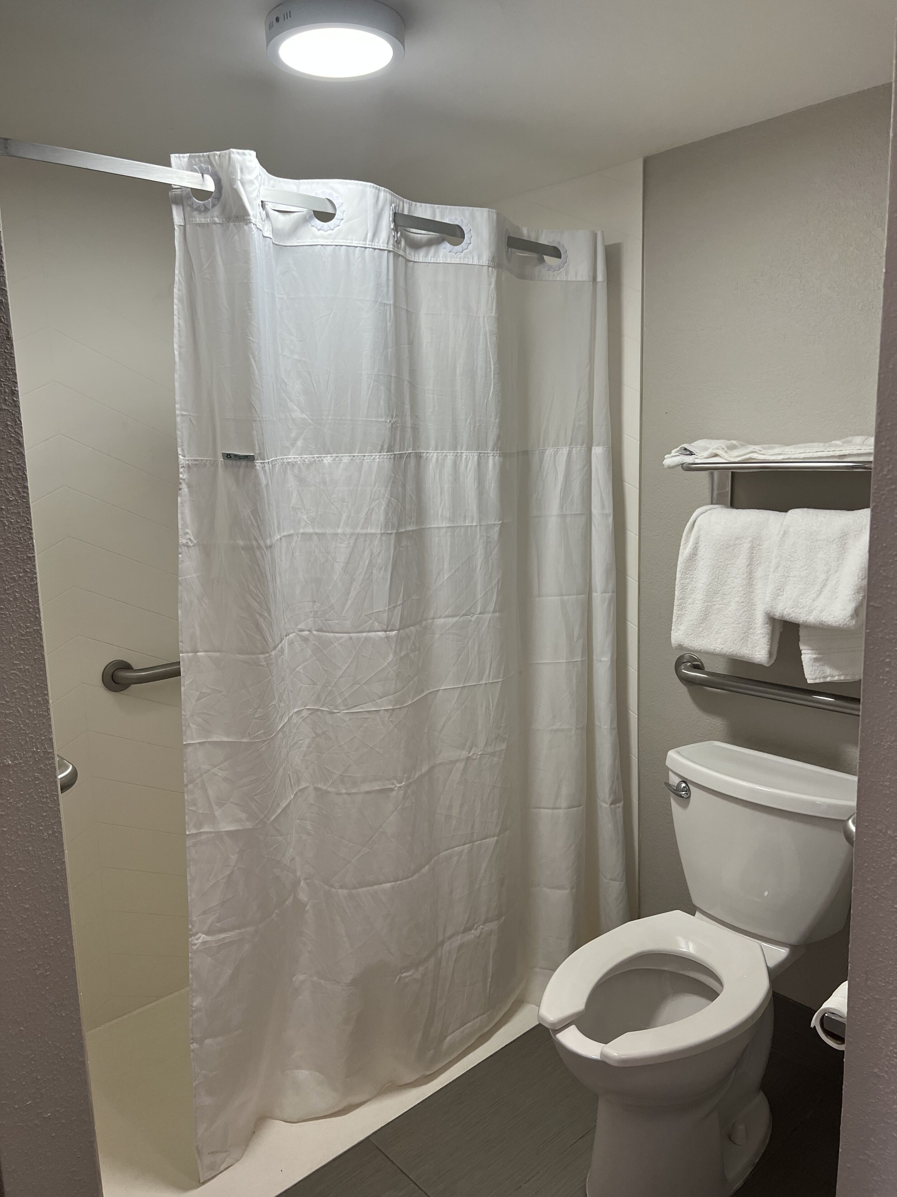 Un baño con cortina de ducha, inodoro y toallero.