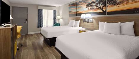 A hotel room with two beds, a desk, a chair, and a TV.