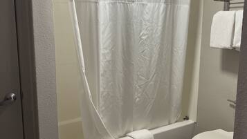 Un baño con bañera, inodoro y cortina de ducha.