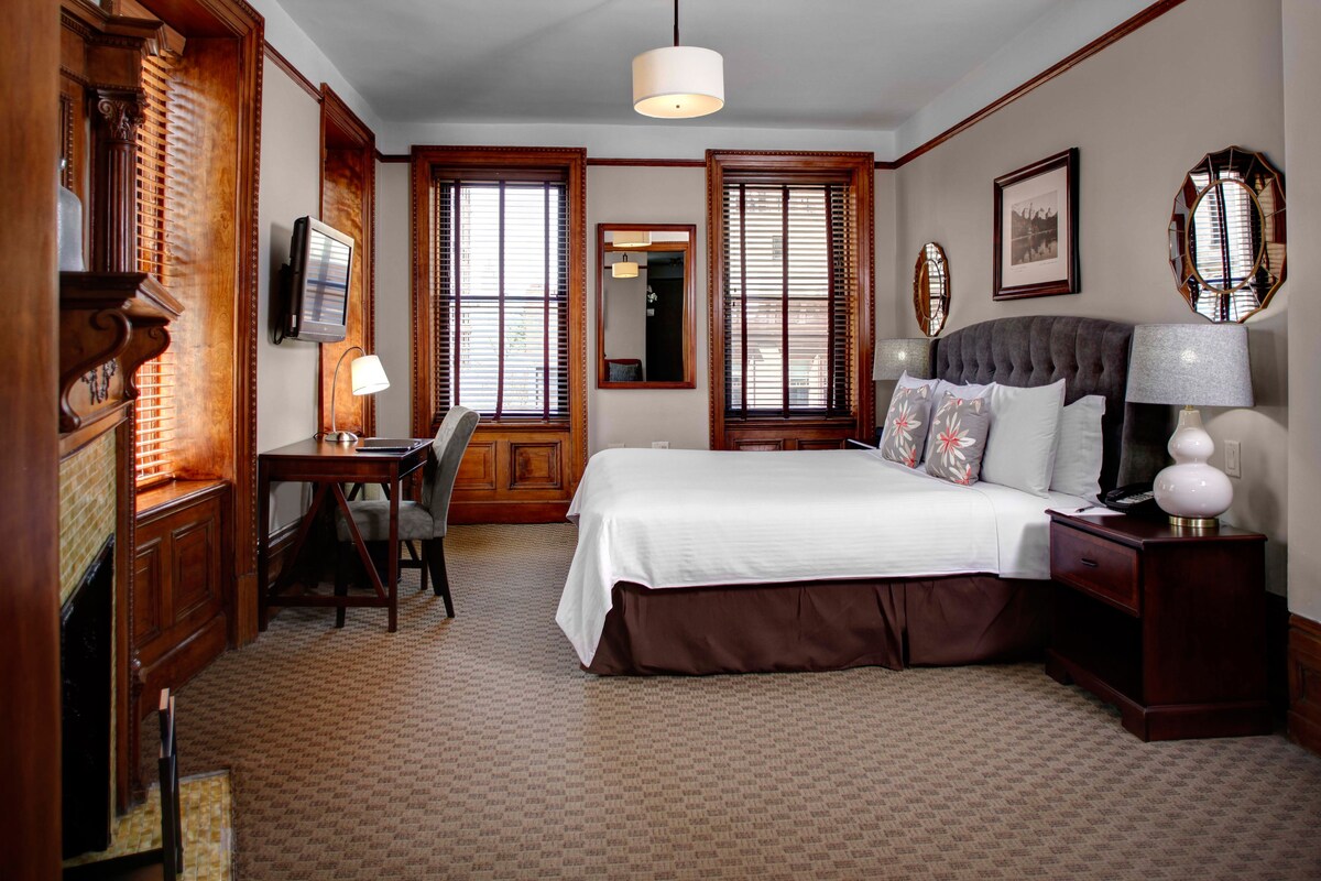 A hotel room with a large bed, wooden furniture, a desk, and a television.