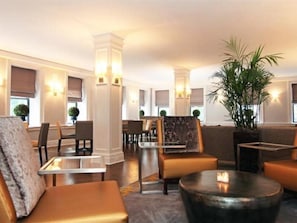 A modern hotel lobby with a seating area, a coffee table, and a large plant. - Hotel Wales (New York)