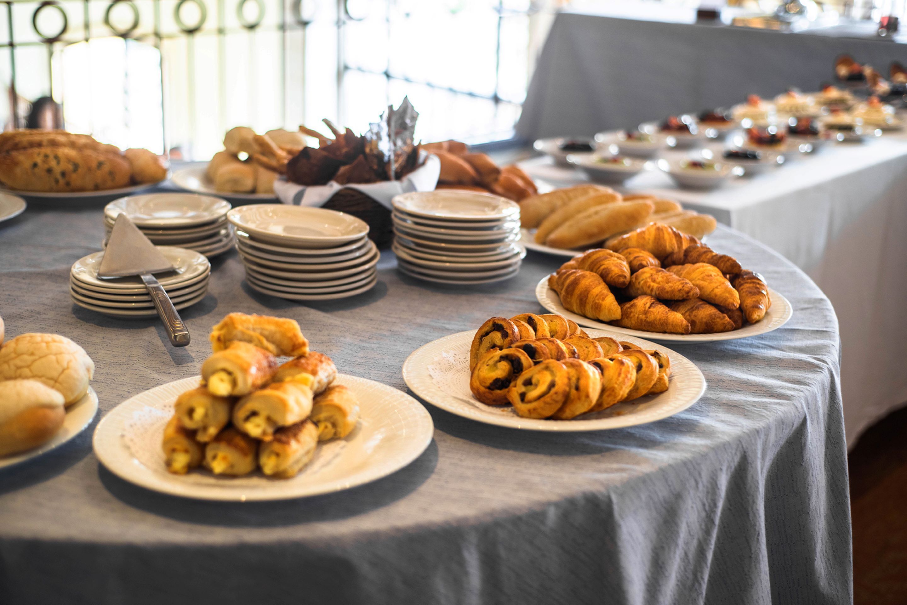 A buffet table with various pastries and breads.