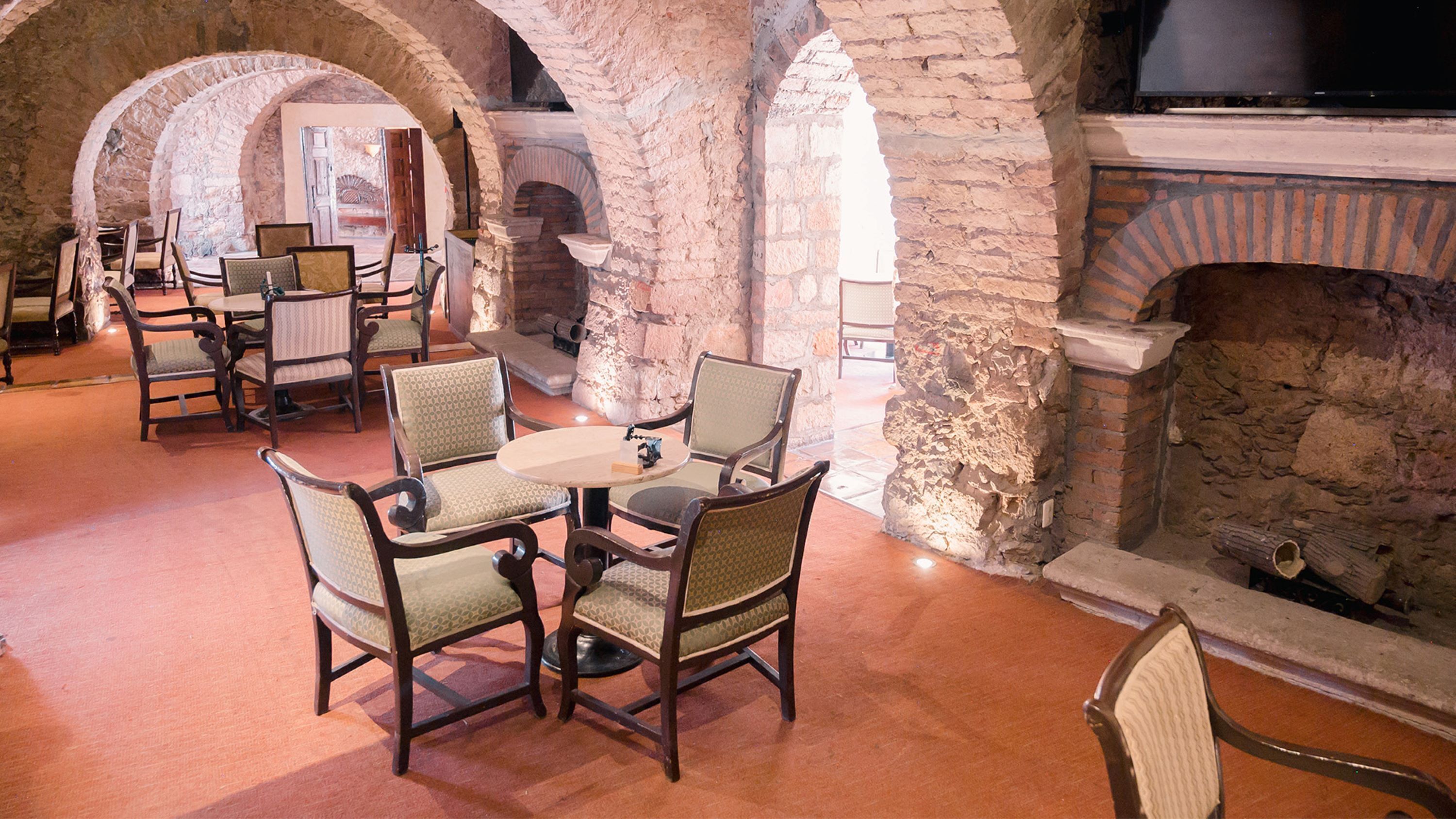A room with stone arches, a fireplace, and a table with chairs.