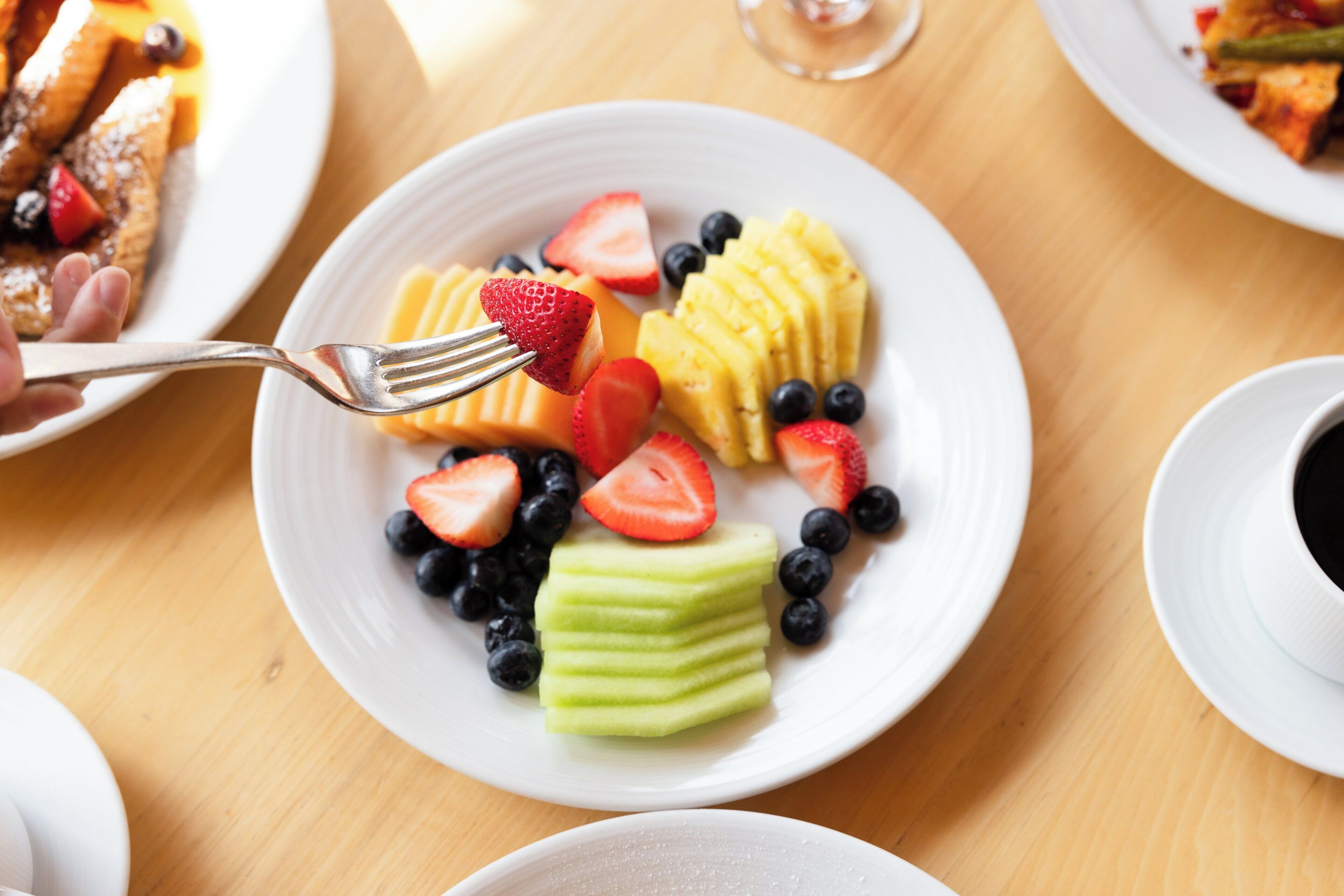 A plate of fruit with strawberries, blueberries, and melon slices.