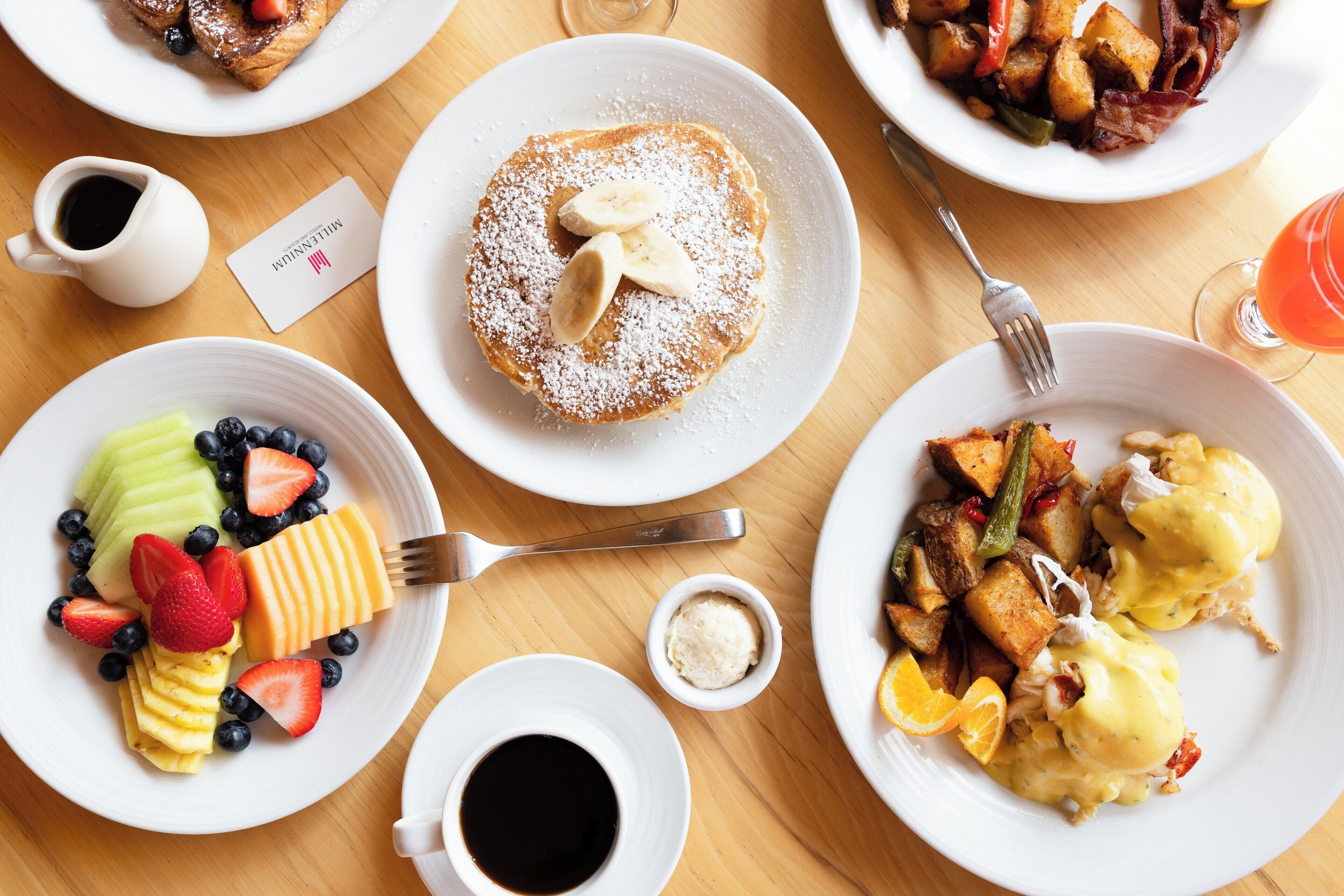 Mesa de café da manhã com diversos pratos, incluindo panquecas, frutas, ovos e torradas.