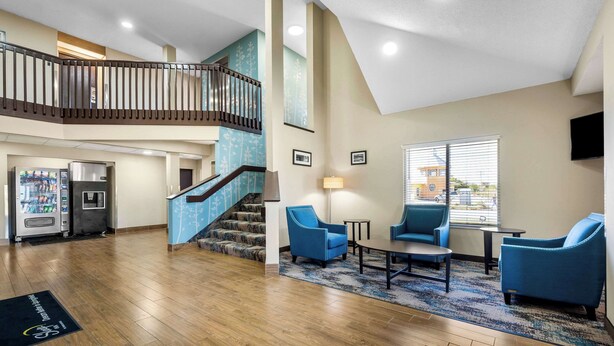 A spacious lobby with a wooden floor, a staircase with a railing, and a seating area with blue chairs and a small table. - Sleep Inn Springfield West (Springfield)