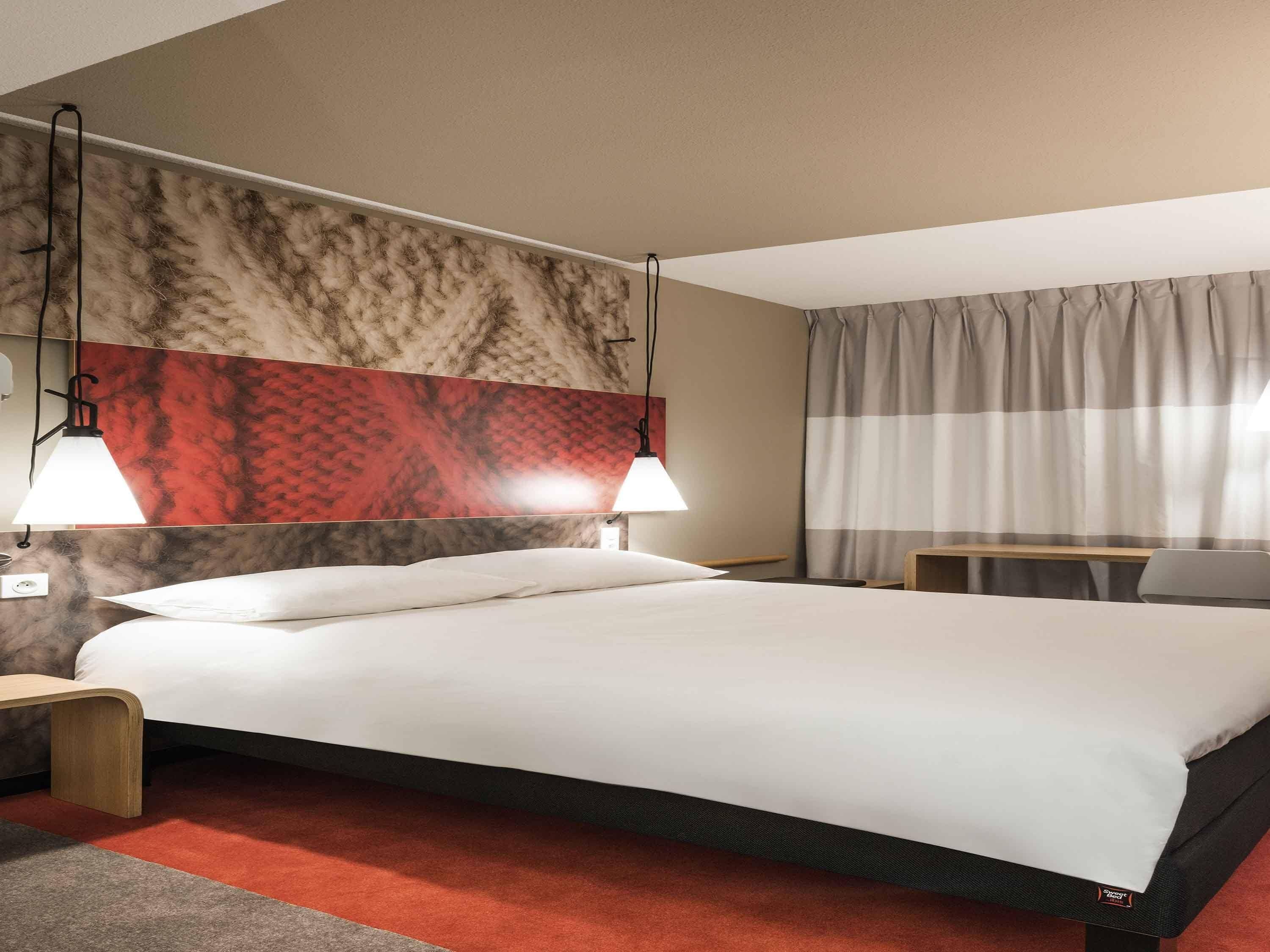 Une chambre d’hôtel comprenant un lit, deux lampes de chevet, une table de chevet, un bureau et une chaise.