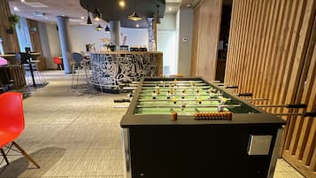 Une table de baby-foot dans un décor intérieur moderne, avec un bar en arrière-plan.