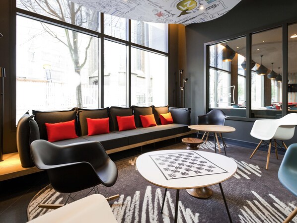 Ein modernes Interieur mit einer Couch, Sesseln, einem runden Tisch und großen Fenstern.