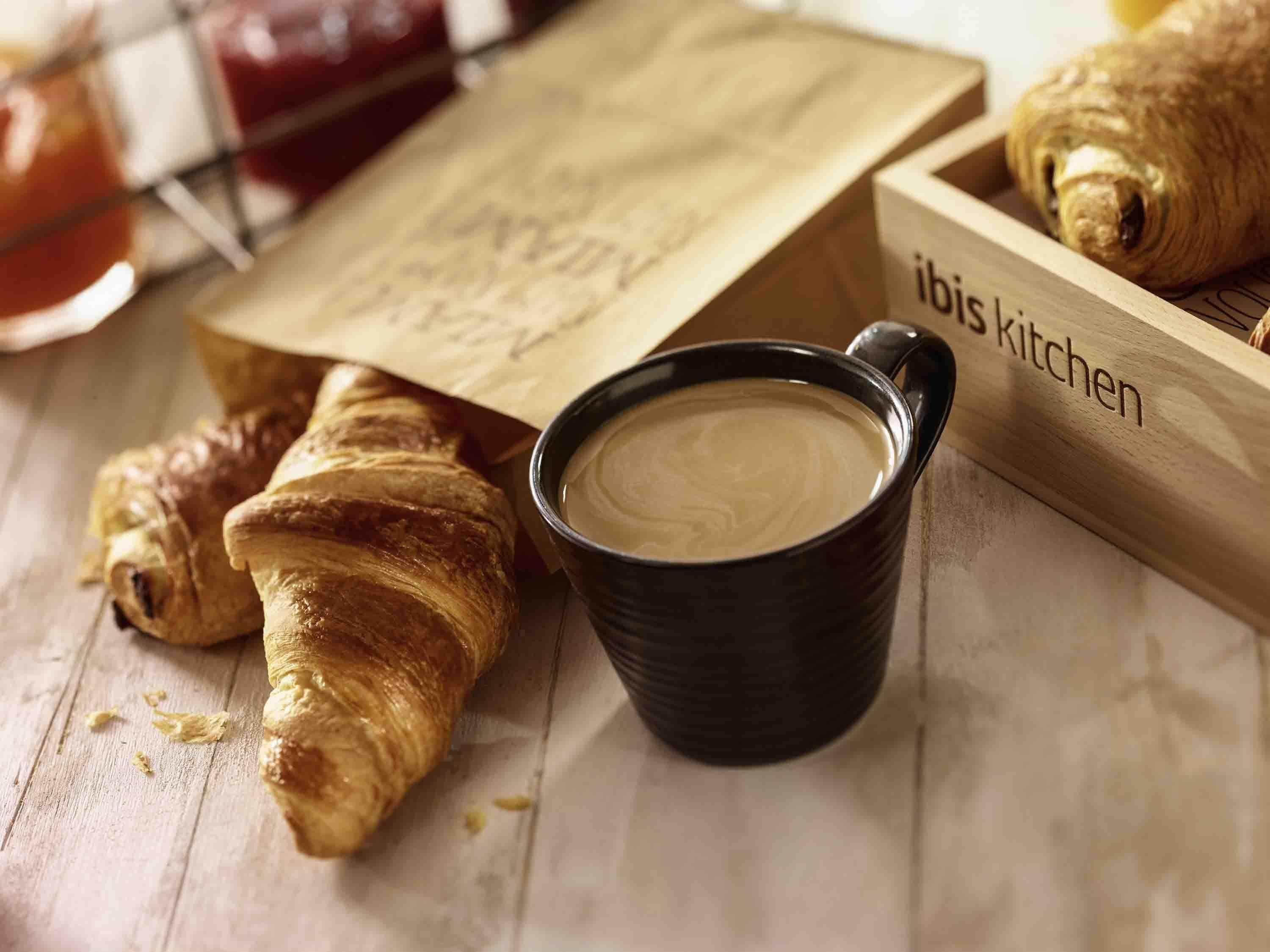Ein Holztablett mit Croissants und einer Tasse Kaffee.