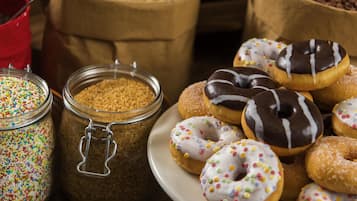 A variety of donuts on a plate, with some covered in chocolate and others with colorful sprinkles.
