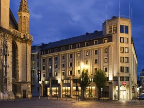 A historic building with a clock tower, adjacent to a modern hotel with multiple floors and large windows. - ibis Gent Centrum St-Baafs Kathedraal (Ghent)