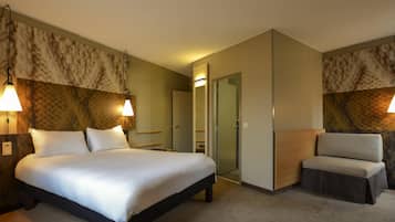 Une chambre d’hôtel comprenant un lit, des tables de chevet, une chaise et une porte donnant sur une salle de bain.