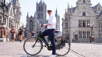 Una persona en bicicleta frente a un edificio histórico de arquitectura gótica.