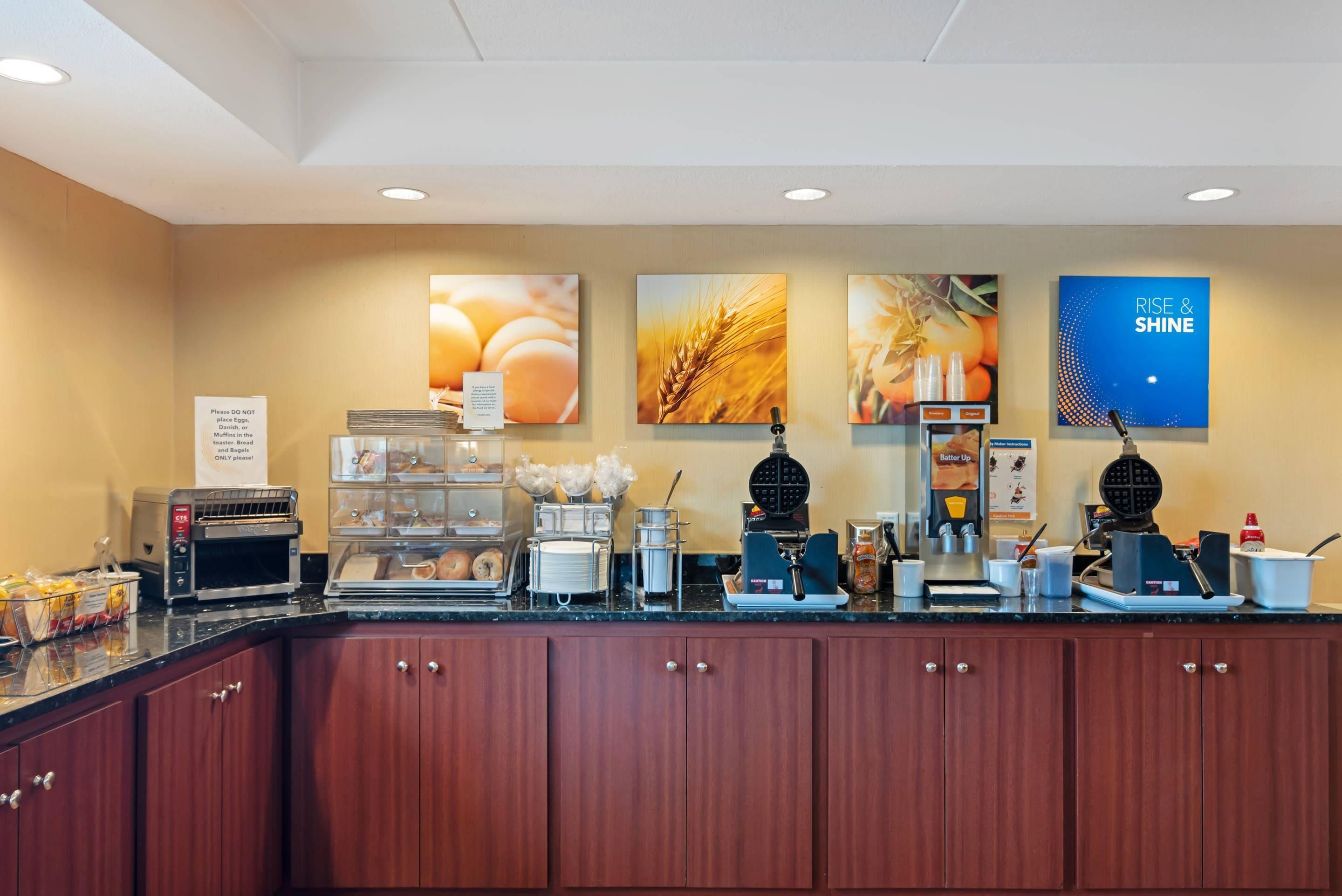 A breakfast bar with a toaster, waffle maker, and coffee machine.