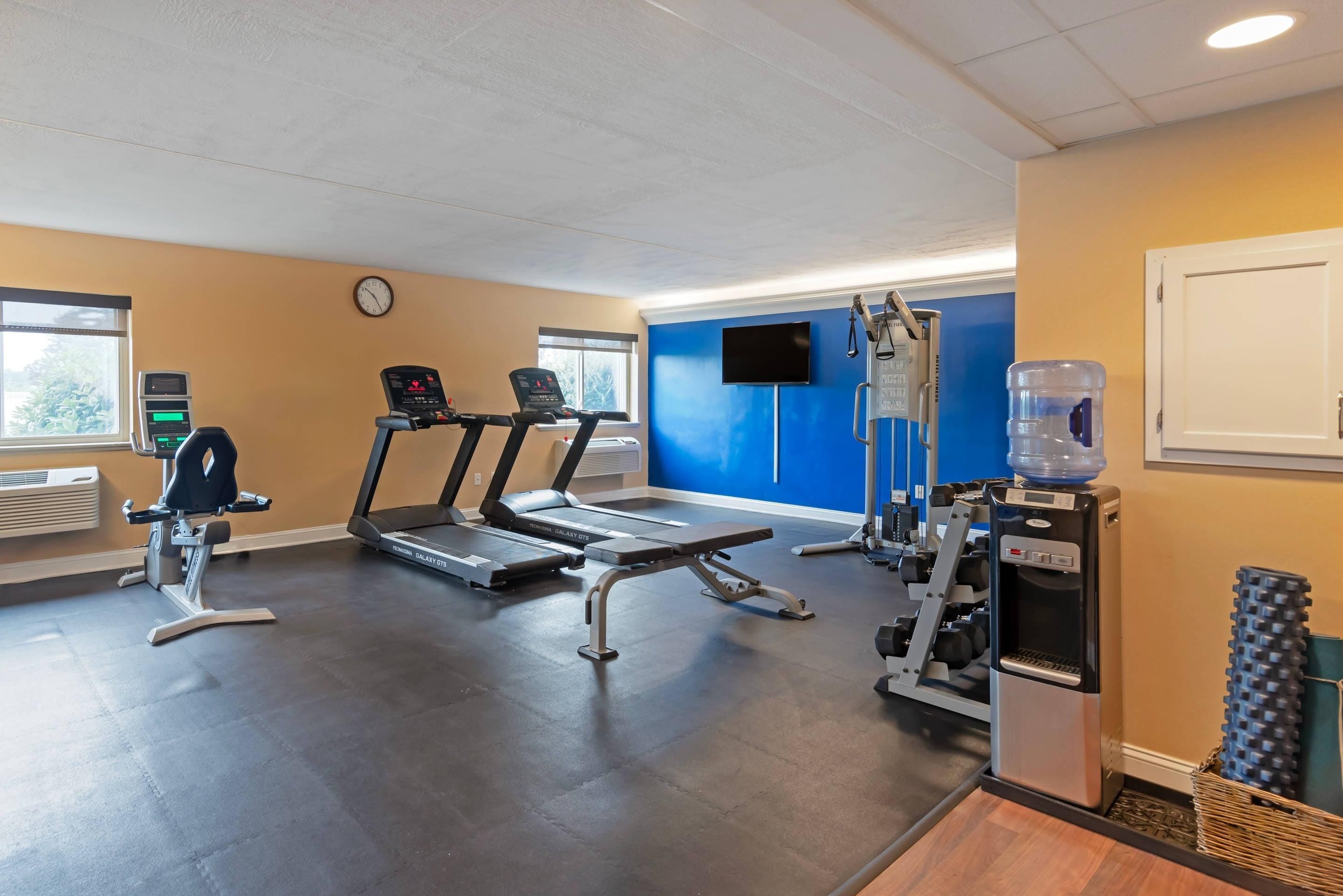 Une salle de sport équipée de tapis de course, d’un vélo d’appartement et de matériel de musculation.