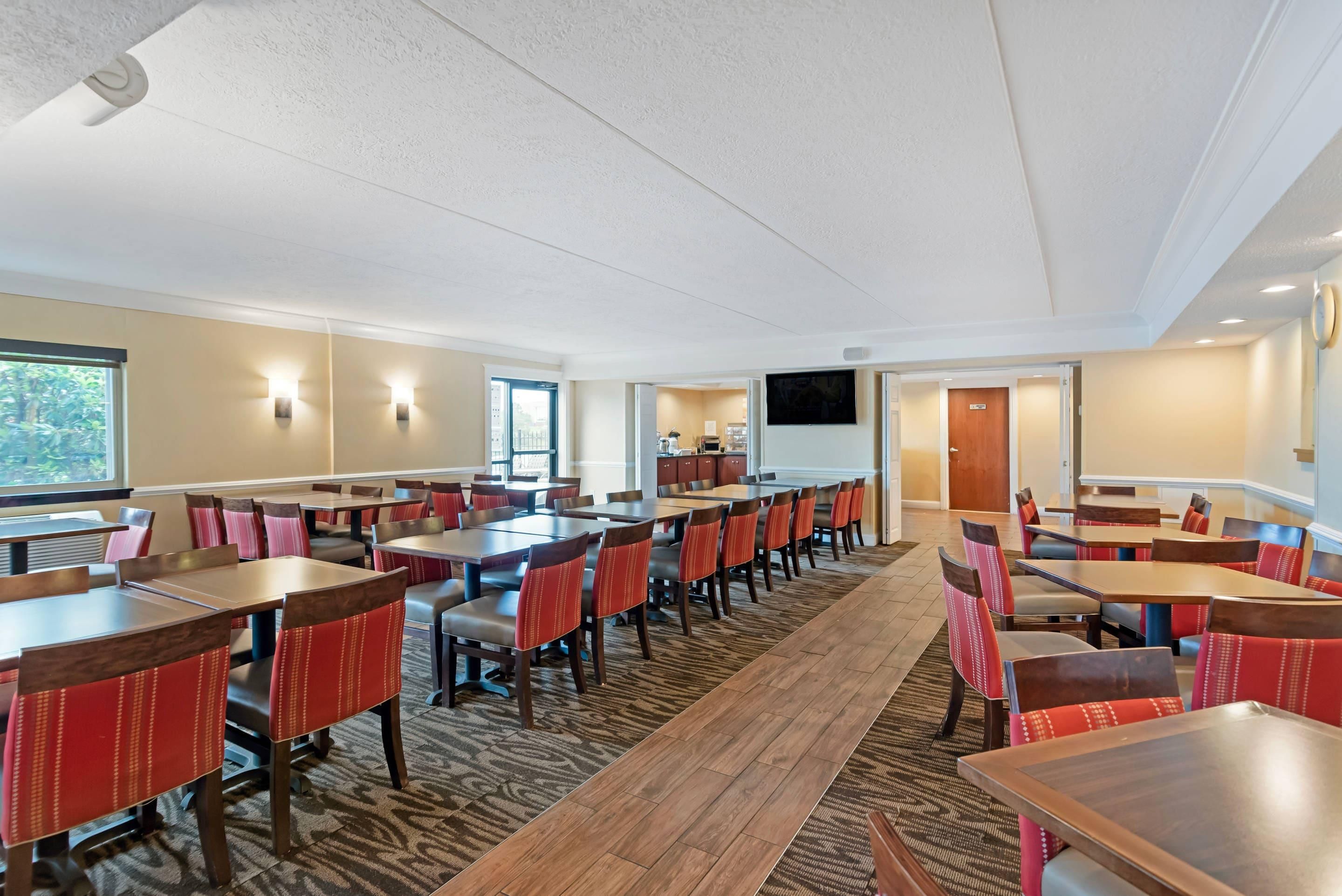 A conference room with multiple tables and chairs, a television screen, and a carpeted floor.
