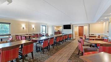 A conference room with multiple tables and chairs, a television screen, and a carpeted floor.