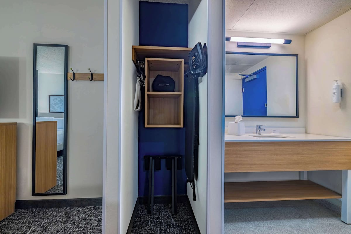 Une salle de bain d’hôtel avec un miroir, un lavabo et des étagères de rangement.