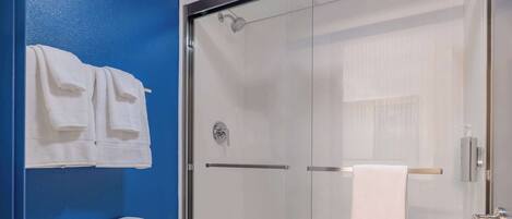 A bathroom with a glass-enclosed shower, a white toilet, and a blue wall.