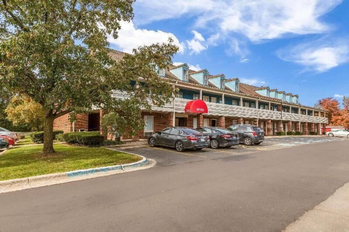 A hotel with a brick facade, multiple parking spaces, and a red awning.