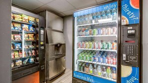 A vending machine with snacks and beverages, a refrigerator, and a beverage max machine. - Travelodge by Wyndham Canton/Livonia Area, MI (Canton)